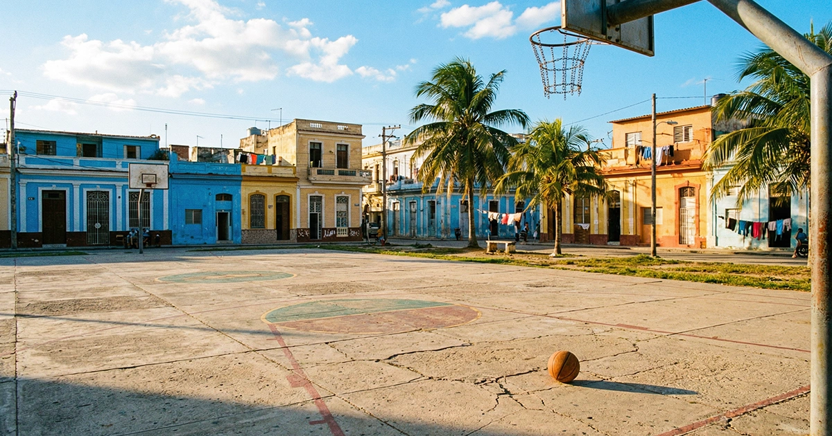 Cancha de baloncesto al aire libre en una ciudad latinoamericana con palmeras y cielo azul de fondo