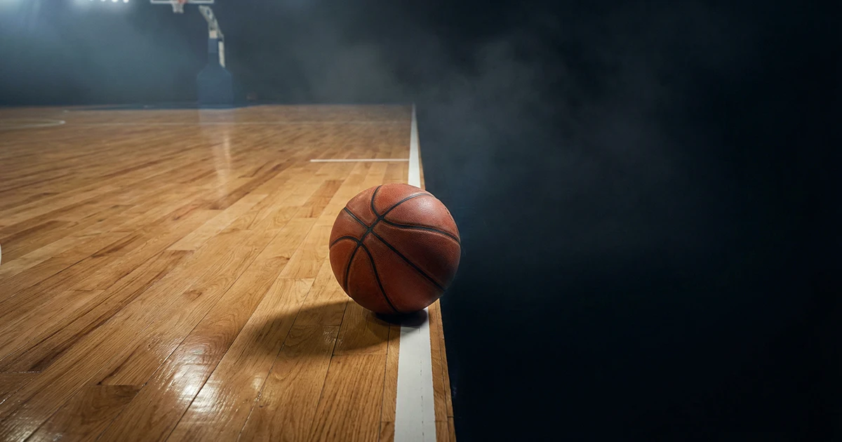 Balón de baloncesto rodando fuera de la cancha hacia la oscuridad del fondo
